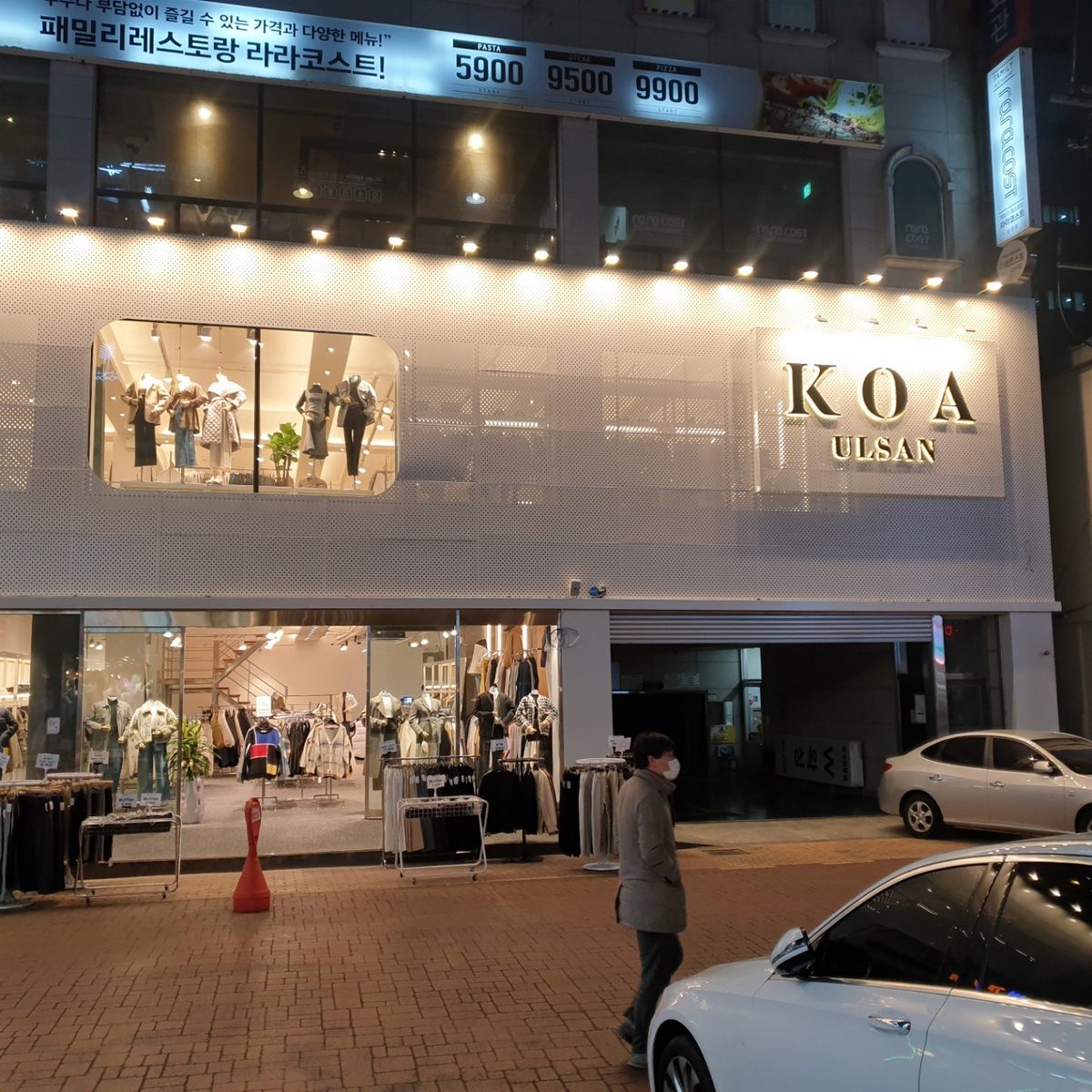 KOA Ulsan at night — a white perforated-metal facade with a lit KOA ULSAN sign